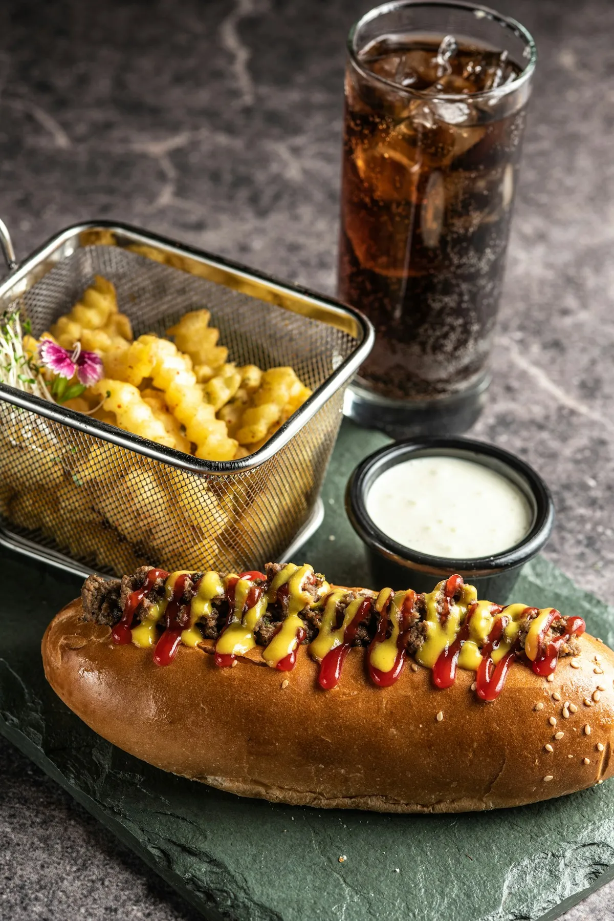 A freshly prepared hot dog with fries and a drink, ready to enjoy.